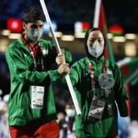 Afghan athletes Hossain Rasouli (left) and Zakia Khudadadi carry their nation\'s flag into the stadium during the closing ceremony. | REUTERS