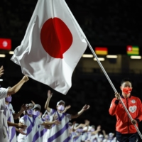 Table tennis player Koyo Iwabuchi carries the Japanese flag during the closing ceremony. | REUTERS