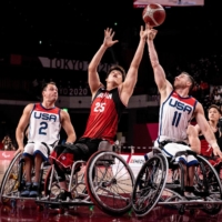 USA\'s Steve Serio (right) and Japan\'s Kei Akita (center) reach for the ball in the wheelchair basketball men\'s final match. | AFP-JIJI