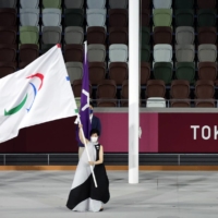 Tokyo Gov. Yuriko Koike waves the Paralympic flag as International Paralympic Committee President Andrew Parsons looks on. | REUTERS
