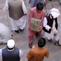 An Afghan money exchange dealer carries bundles of banknotes at an exchange market in Kabul on Saturday.

 | REUTERS
