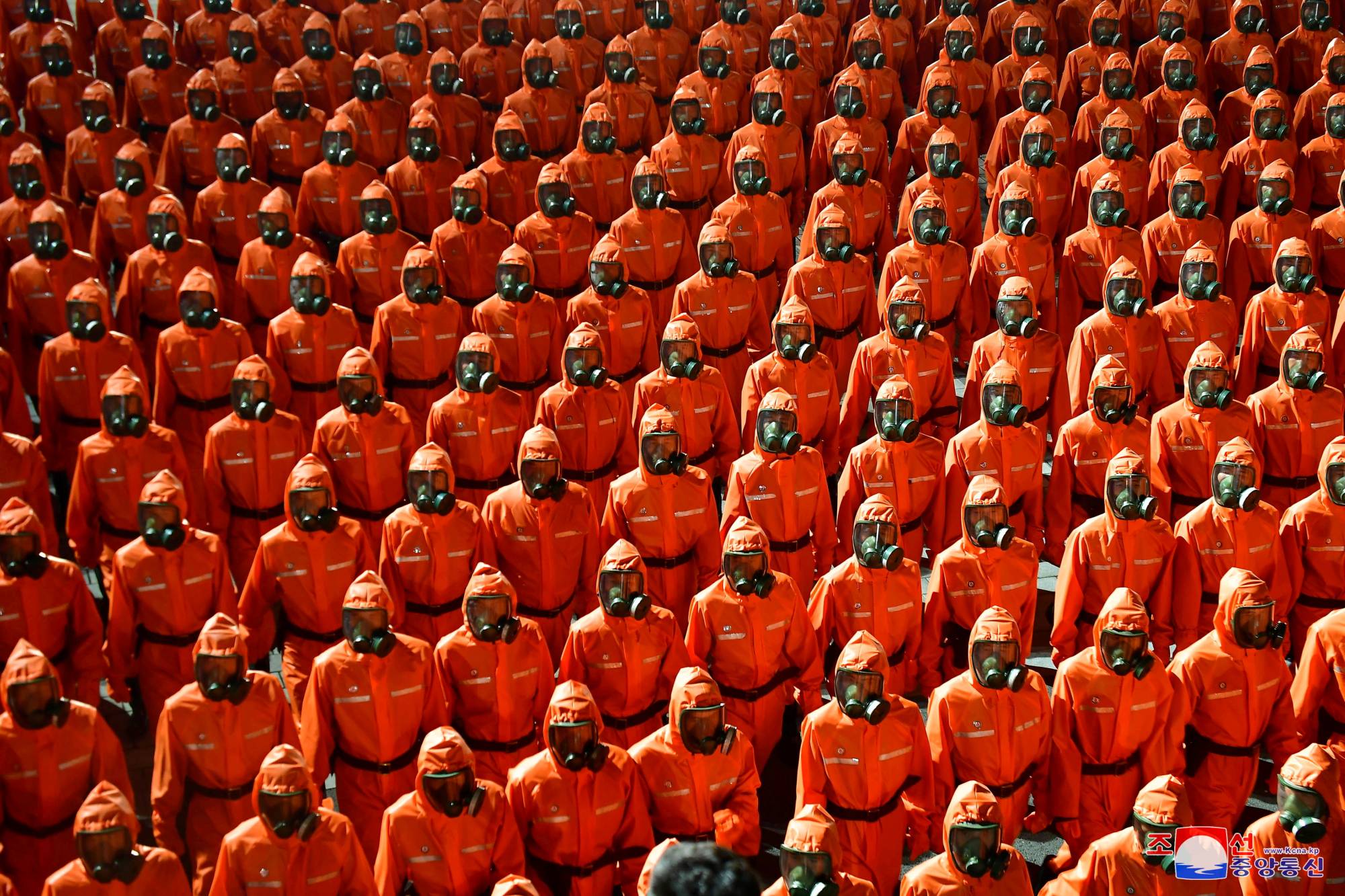 North Korean personnel in orange hazmat suits march during a military parade held to mark the 73rd founding anniversary of the country in Pyongyang's Kim Il Sung Square in this image released Thursday. | KCNA / VIA REUTERS
