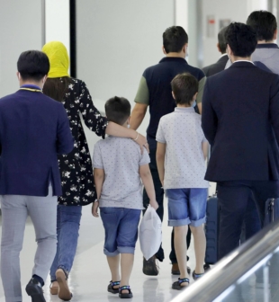 Passengers who are believed to be Afghan evacuees (second from left to fifth from left) arrive at Narita Airport on Sunday evening. | KYODO