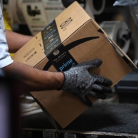 A worker assembles a box for delivery at the Amazon fulfillment center. The e-commerce giant is set to raise wages in the U.S. and hire another 125,000 employees. | REUTERS