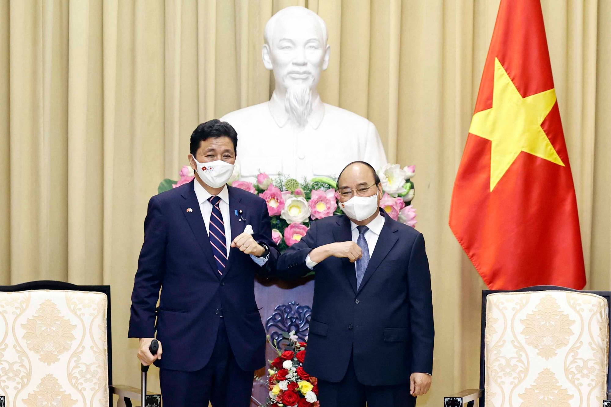 Vietnam's President Nguyen Xuan Phuc (R) bumping elbows to greet Japan's Defence Minister Nobuo Kishi during a meeting in Hanoi on Sunday. | VIETNAM NEWS AGENCY / AFP-JIJI