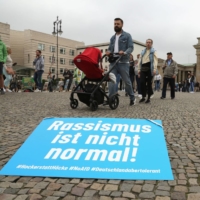 A sign reading \"Racism is not normal,\" referring to the Alternative for Germany party slogan \"Germany, but normal\" during a demonstration on Sept. 4 in Berlin | AFP-JIJI