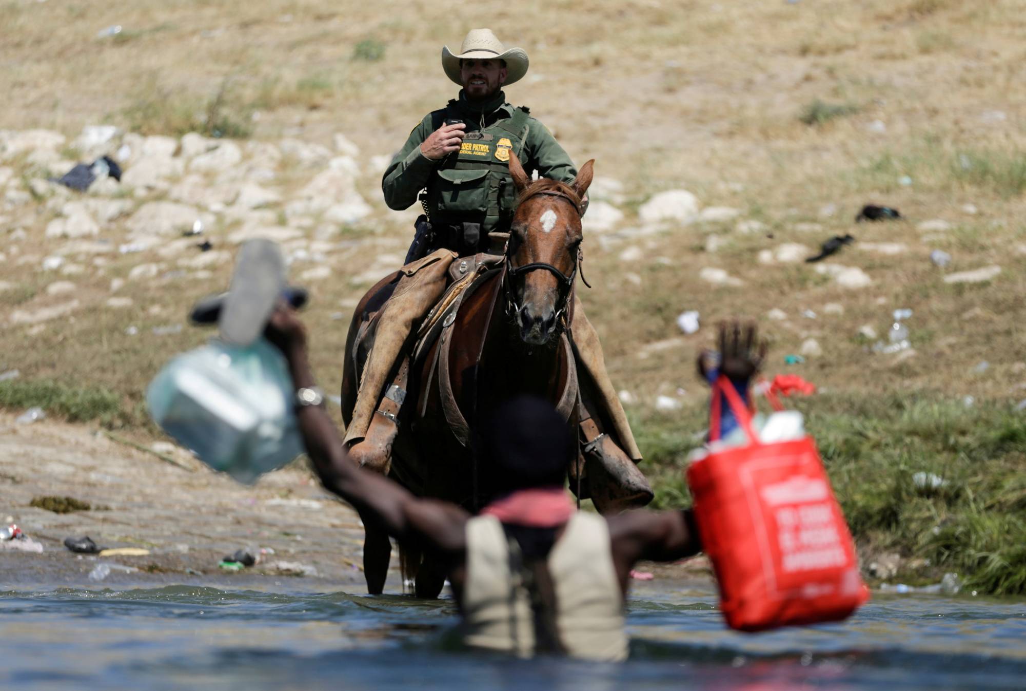 A U.S. border patrol officer cuts the way of a migrant asylum-seeker as he is trying to return to the United States along the Rio Grande river, after having crossed into Mexico to buy food, as seen from Ciudad Acuna, Mexico, on Sunday.  | REUTERS 