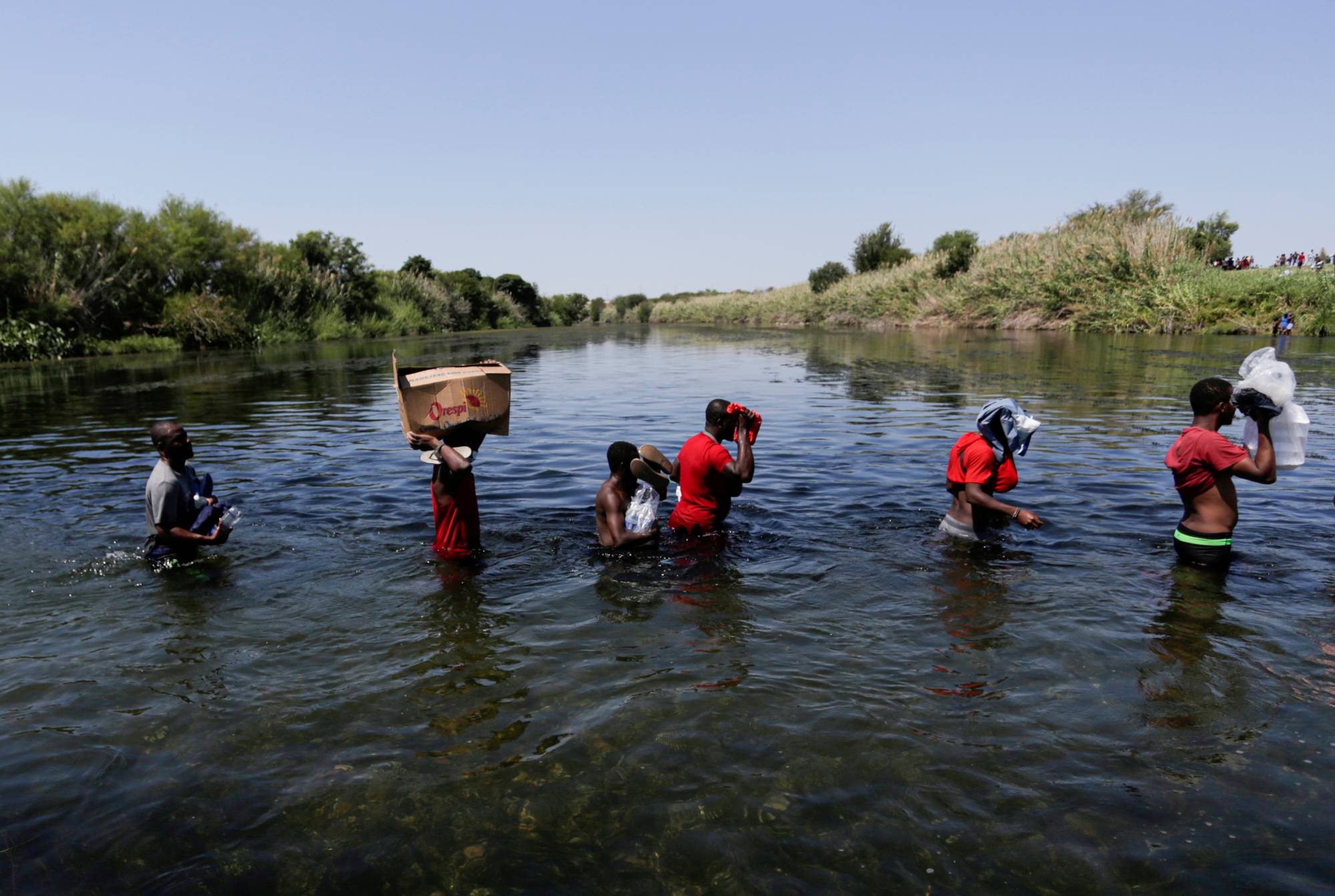 Asylum-seekers walk through the Rio Grande river on Sunday to cross the border between Ciudad Acuna, Mexico, and Del Rio, Texas. | Reuters 