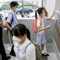 Students have their temperatures checked in Hong Kong.  | REUTERS 
