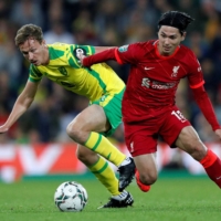 Liverpool midfielder Takumi Minamino right) vies for the ball with Norwich midfielder Kieran Dowell on Tuesday in Norwich, England. | AFP-JIJI