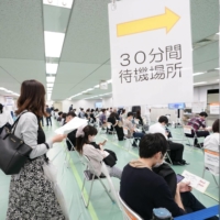 People wait to receive a COVID-19 vaccine shot earlier this month at a mass vaccination site in Tokyo run by the Self-Defense Forces. | KYODO