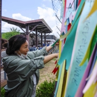 A visitor looks at a fence adorned with ribbons at a peace park in Paju, South Korea, near the Demilitarized Zone separating the two Koreas.  | AFP-JIJI