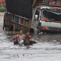 Children wade along a flooded street after a heavy downpour in Lahore, Pakistan, on Sept. 11. | AFP-JIJI