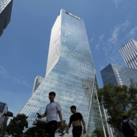 People walk past the headquarters of China Evergrande Group in Shenzhen, China, on Sunday. | REUTERS