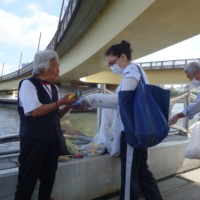 Members of Sanyukai, a nonprofit helping homeless people in Sanya, Taito Ward, hand out goods to people living by Sumida River on Sept. 22. | ALEX K.T. MARTIN