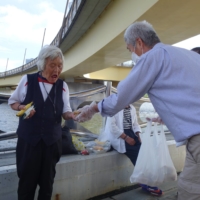 Members of Sanyukai, a nonprofit helping the homeless in Sanya, Taito Ward, hand out supplies to homeless people living by the Sumida River on Sept. 22. | ALEX K.T. MARTIN
