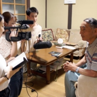 Three students at Hiroshima University of Economics interview Masaaki Takano, head of a \"black rain\" plaintiffs group, at his home. | CHUGOKU SHIMBUN
