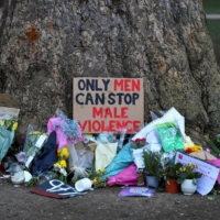 Signs and flowers are left under a tree near the Clapham Common Bandstand in London on March 17, following the kidnap and murder of Sarah Everard. | REUTERS