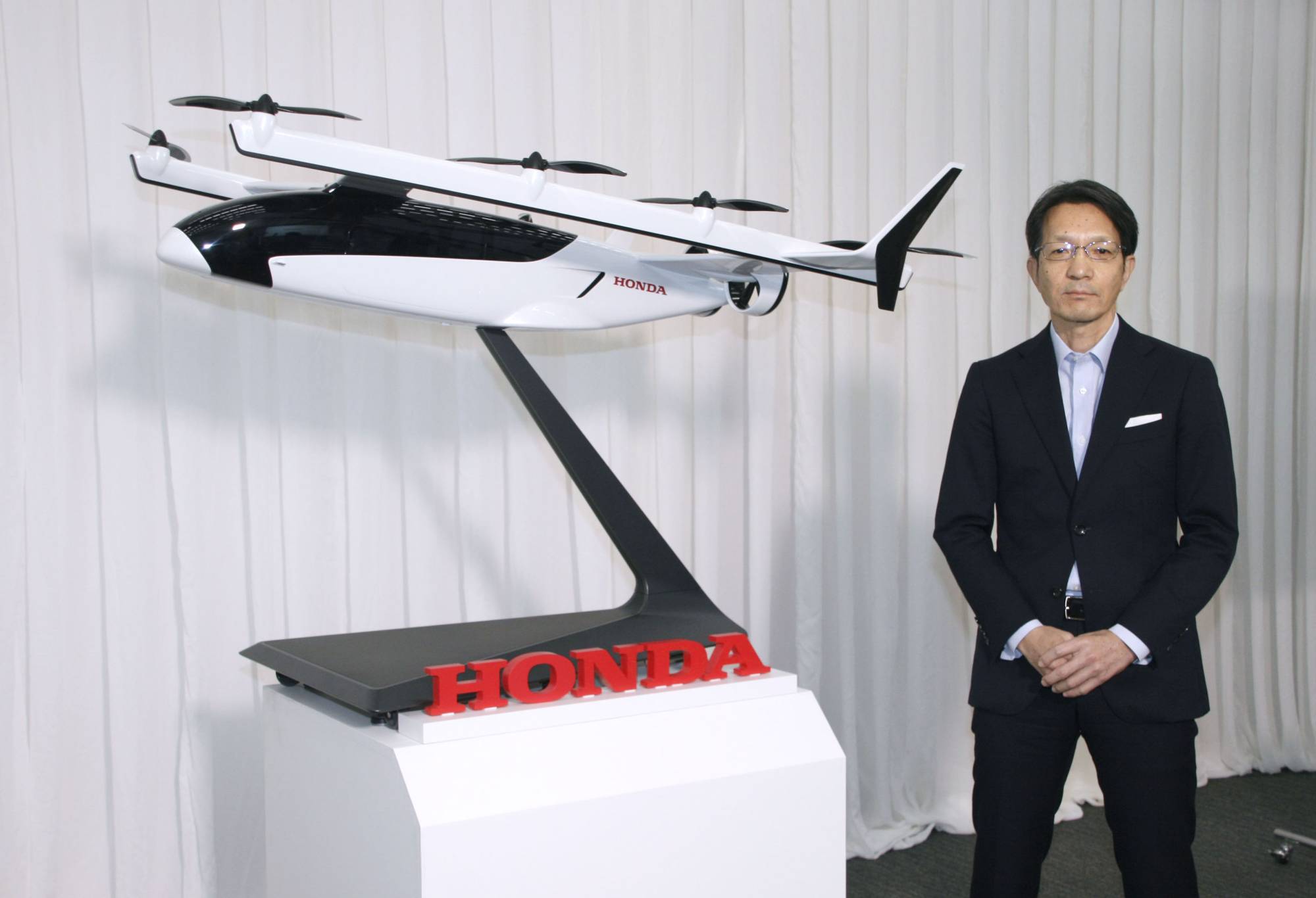 Honda R&D Co. President Keiji Otsu shows a model for the firm's electric vertical takeoff and landing (eVTOL) vehicles in Wako, Saitama Prefecture, on Tuesday. | KYODO