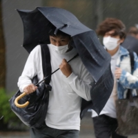 People walk through heavy rain and wind in Tokyo on Friday. | REUTERS