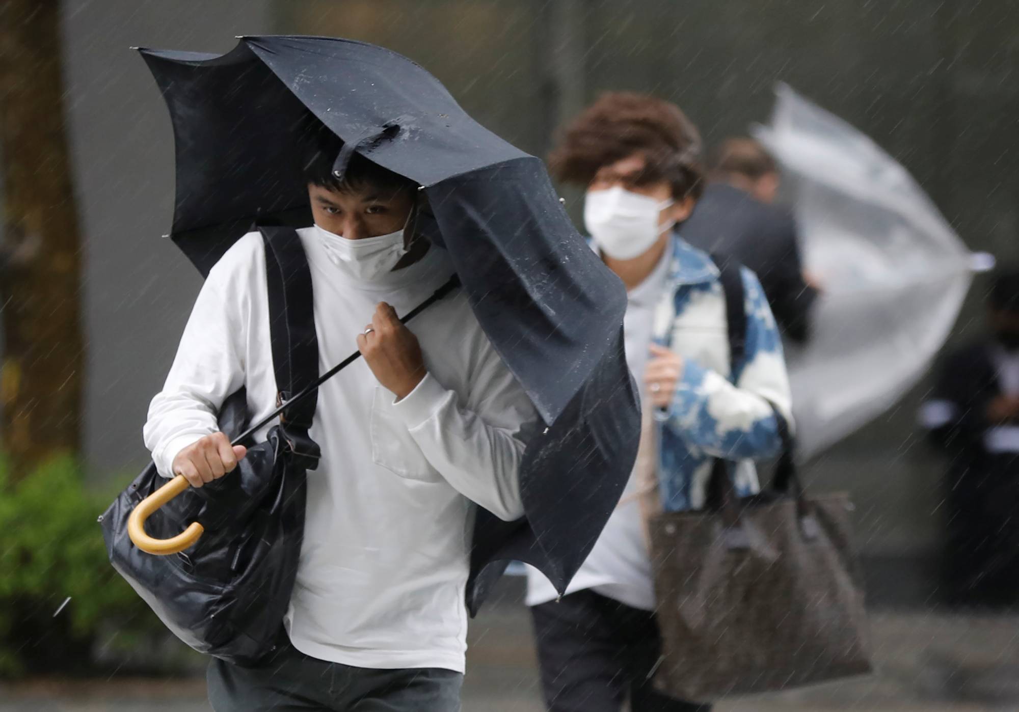 People walk through heavy rain and wind in Tokyo on Friday. | REUTERS
