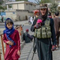 A Taliban fighter poses for a picture holding a flower before offering prayers in Kabul on Friday. | AFP-JIJI