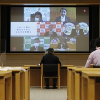 Members of the National Governors\' Association are seen on a screen in Tokyo during an online meeting Saturday. | KYODO