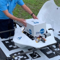 Members of Aeronext Inc. load a box of goods onto a drone at Kosuge Village. The drone startup is experimenting with on-demand drone deliveries in the small community in Yamanashi Prefecture. | COURTESY OF AERONEXT INC.
