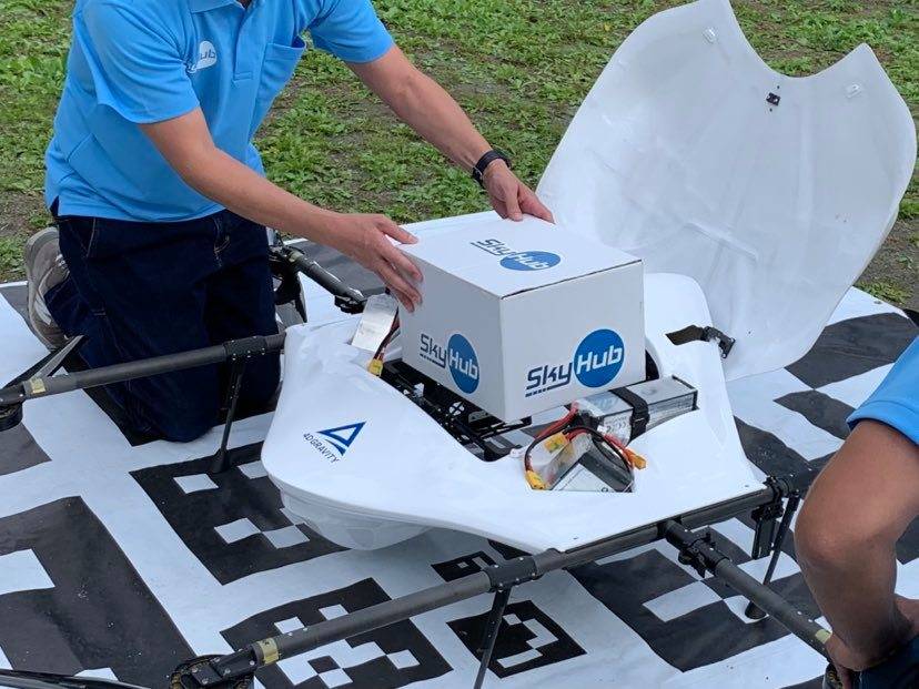 Members of Aeronext Inc. load a box of goods onto a drone at Kosuge Village. The drone startup is experimenting with on-demand drone deliveries in the small community in Yamanashi Prefecture. | Courtesy of Aeronext Inc. 