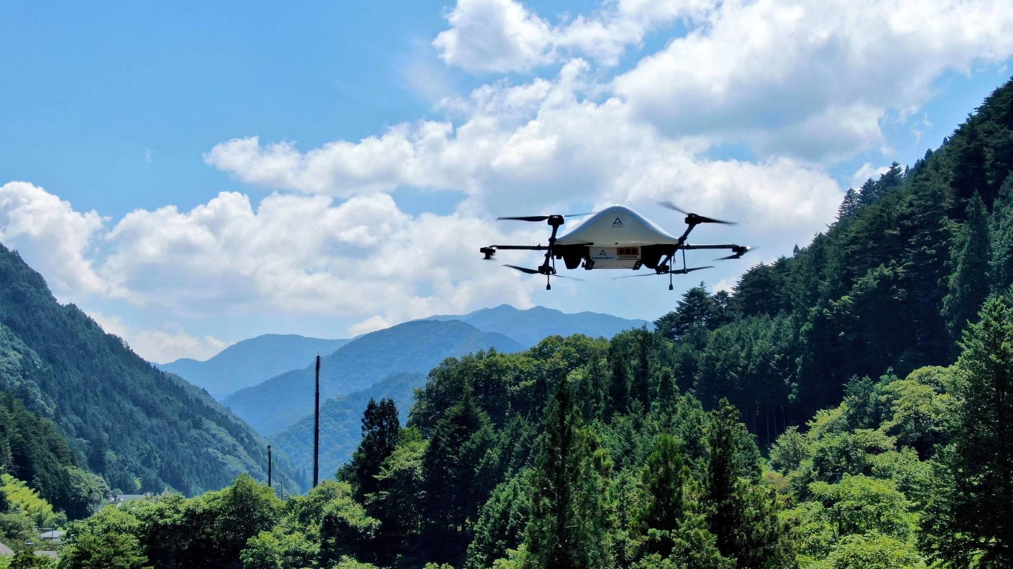 Aeronext Inc.'s drone flies over the mountains around Kosuge Village in Yamanashi Prefecture. The company hopes drone deliveries will solve the last-mile logistical conundrum many rural communities in Japan are facing. | COURTESY OF AERONEXT INC.