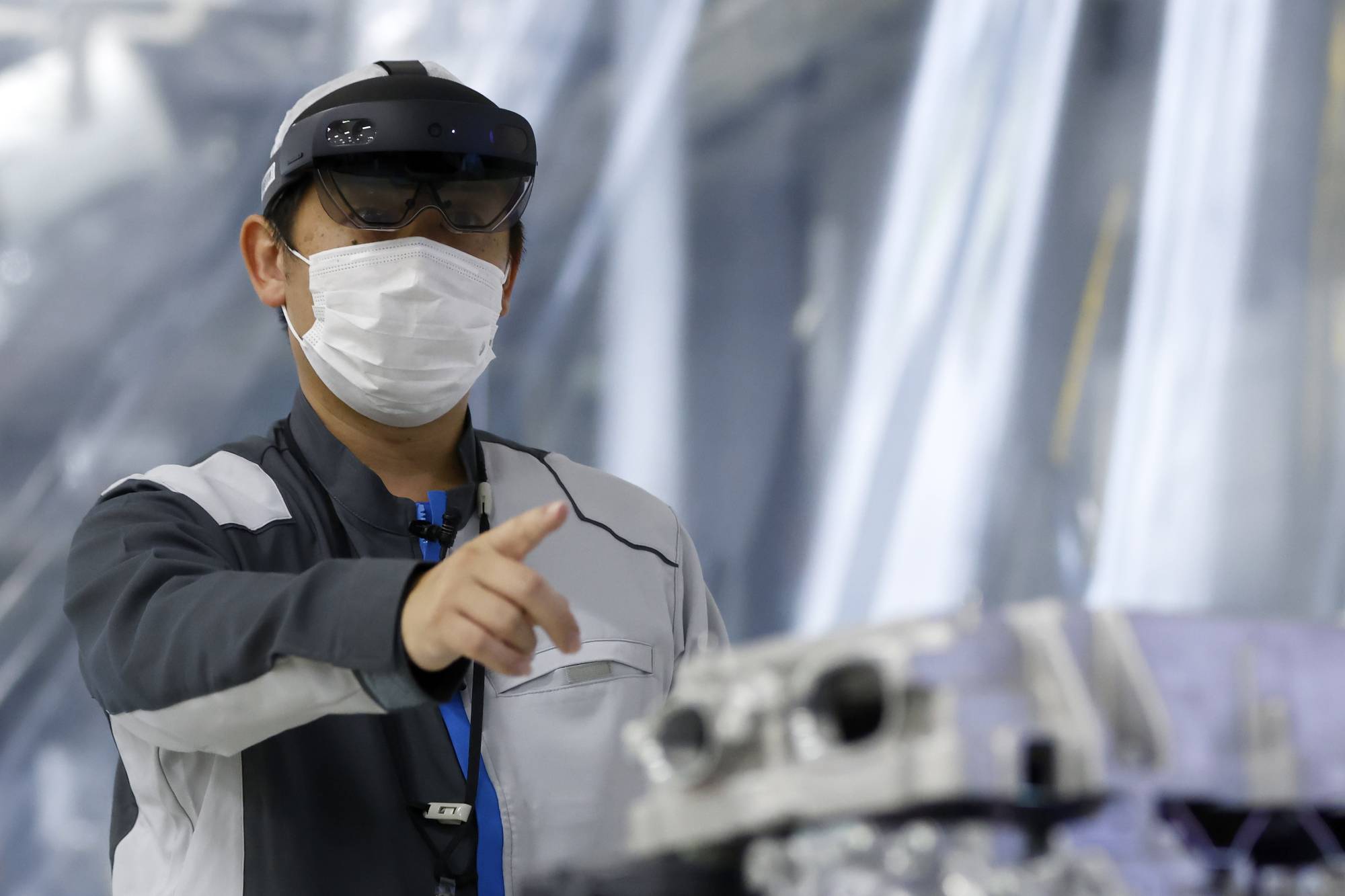 An employee wearing mixed reality goggles demonstrates the intelligent operation support system at Nissan Motor Co.'s plant in Kaminokawa, Tochigi Prefecture, on Thursday. | BLOOMBERG
