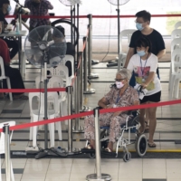 A resident prepares to receive her COVID-19 vaccine in Singapore in September. | BLOOMBERG 