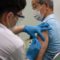 A health worker administers a dose of Moderna Inc.\'s COVID-19 vaccine at a mass vaccination site in Tokyo in May. | GETTY IMAGES / VIA BLOOMBERG