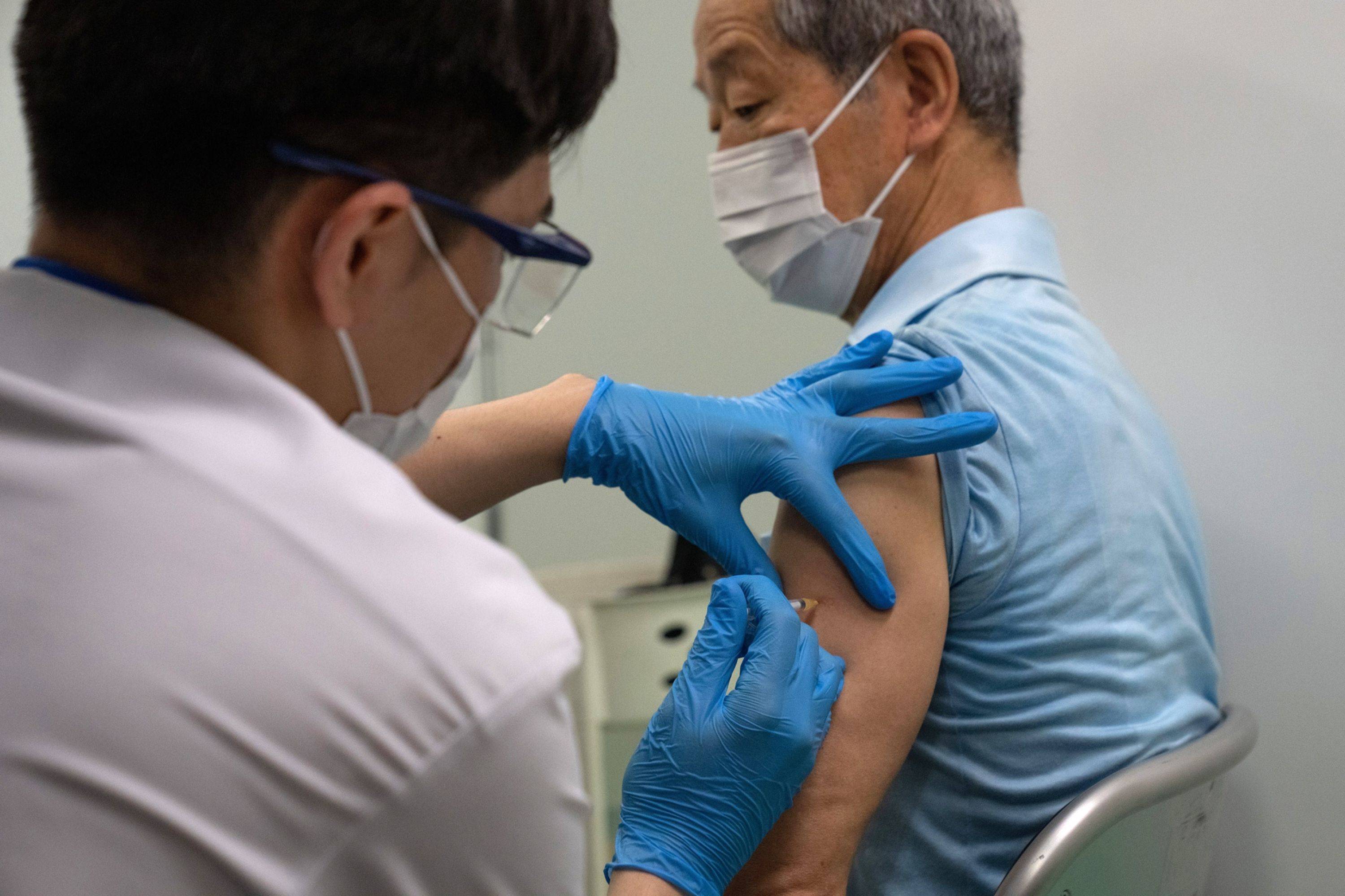 A health worker administers a dose of Moderna Inc.'s COVID-19 vaccine at a mass vaccination site in Tokyo in May. | GETTY IMAGES / VIA BLOOMBERG