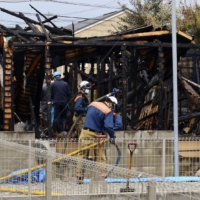 Firefighters Tuesday investigate a house in Kofu, Yamanashi Prefecture, which was burned down in a suspected arson. | KYODO