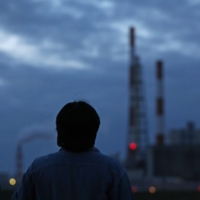 A former employee looks up at the chimney of Nippon Paper Industries\' factory in Kushiro, Hokkaido, after its closure. | HOKKAIDO SHIMBUN
