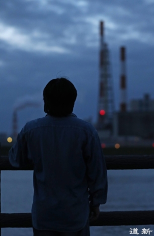 A former employee looks up at the chimney of Nippon Paper Industries' factory in Kushiro, Hokkaido, after its closure. | HOKKAIDO SHIMBUN