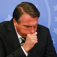 Brazil\'s President Jair Bolsonaro coughs during a ceremony at the Planalto Palace in Brasilia on Wednesday. | REUTERS