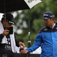 Hideki Matsuyama (right) gets a ball from caddie Shota Hayafuji on the 10th hole during the second round of the Zozo Championship at Narashino Country Club in Inzai, Chiba Prefecture, on Friday. | AFP-JIJI