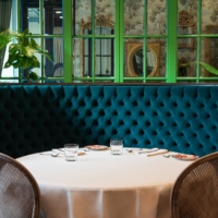 The dining room at Gucci Osteria Tokyo is painted a vibrant olive green and decorated with antique mirrors. | HIROKI KOBAYASHI 
