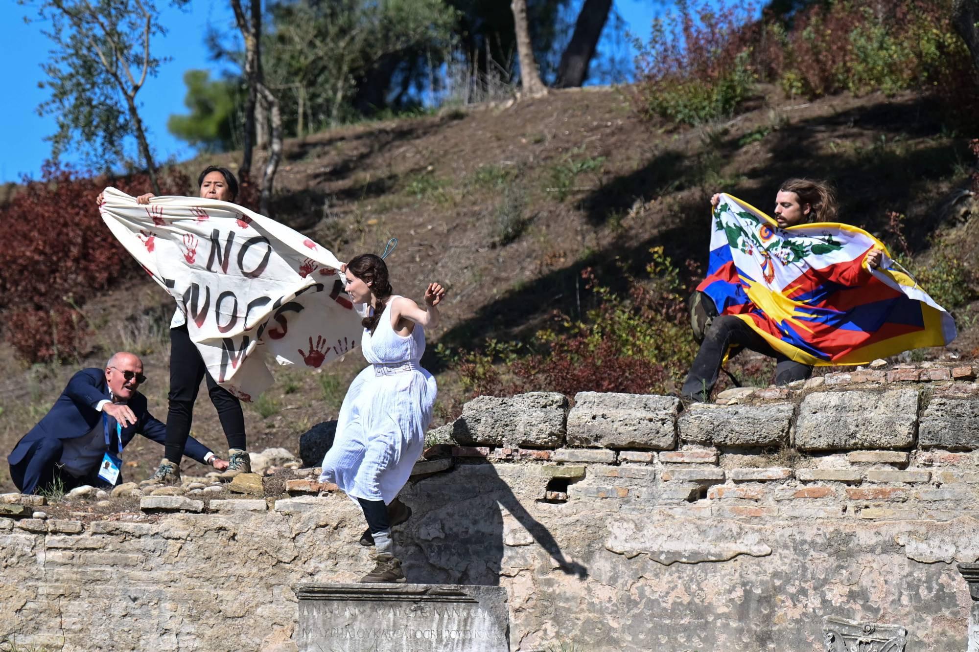 A security official tries to stop protesters holding the Tibetan flag and banner as they crash the flame lighting ceremony for the Beijing 2022 Winter Olympics at the Ancient Olympia archeological site, birthplace of the Olympics, in southern Greece on Oct. 18. | AFP-JIJI