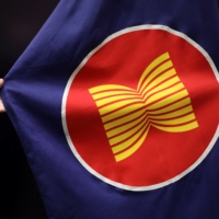 A worker adjusts an ASEAN flag at a meeting hall in Kuala Lumpur on Thursday. | REUTERS