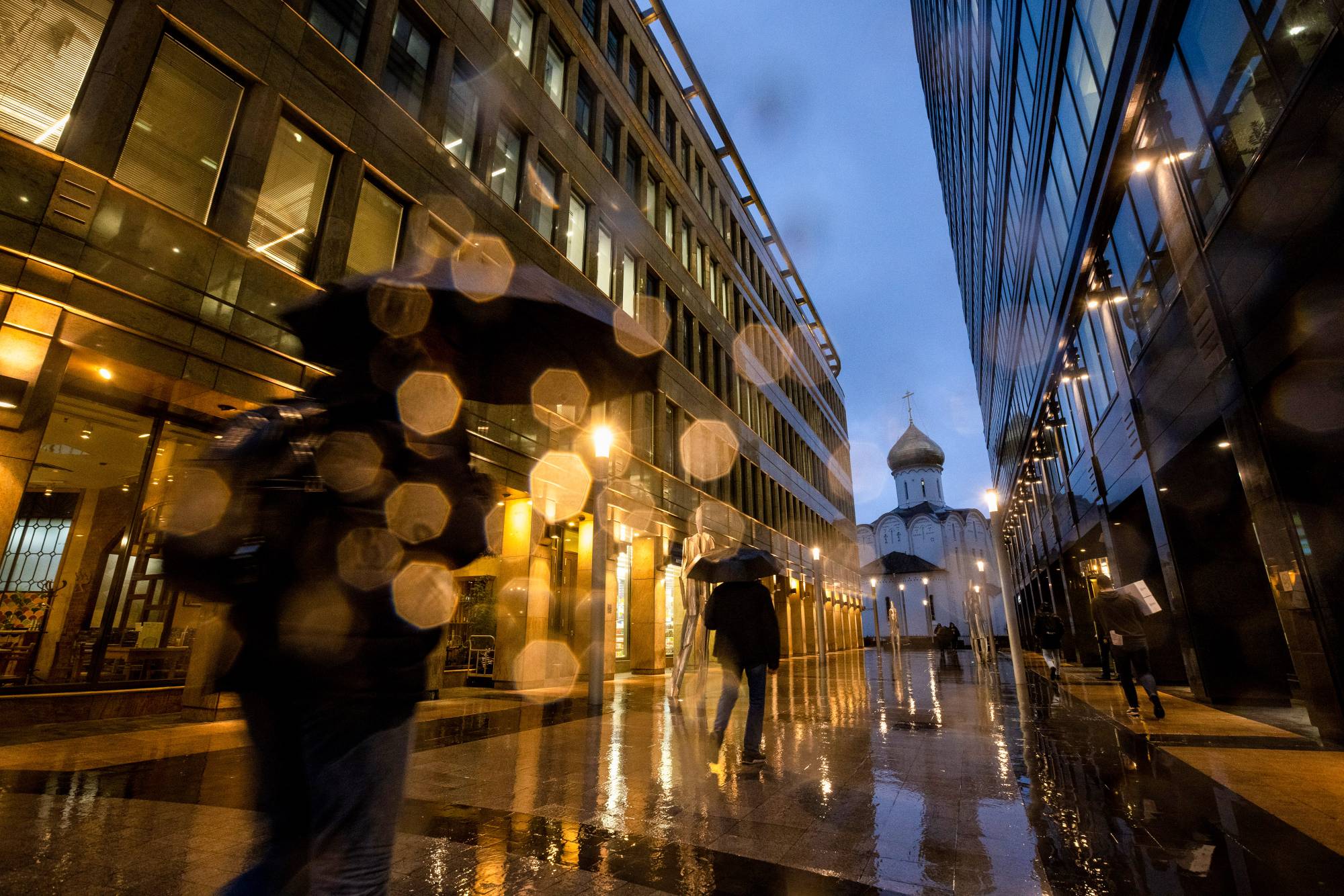 Pedestrians walk in the rain in Moscow on Thursday, Oct. 28, 2021. One of the world’s largest fossil-fuel producers, Russia has had green conversion, but it may complicate negotiations at next week’s COP26 summit. | BLOOMBERG