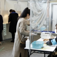 Voters cast ballots at an early voting location in Tokyo\'s Minato Ward on Thursday, ahead of Sunday\'s Lower House election. | BLOOMBERG