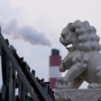 A chimney of a coal-fired power plant behind a lion statue in Shanghai | REUTERS 
