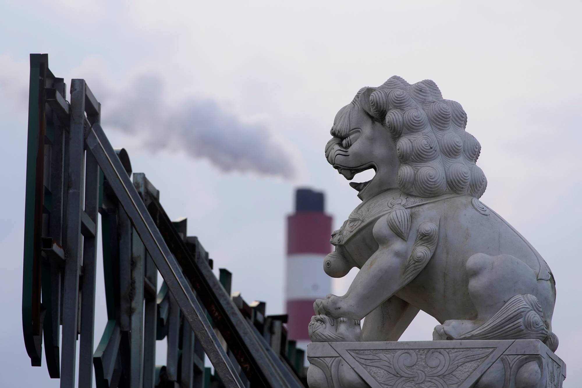 A chimney of a coal-fired power plant behind a lion statue in Shanghai | Reuters 