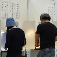 Voters cast ballots at an early polling location in the Minato Ward of Tokyo on Thursday. | BLOOMBERG