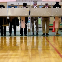Voters fill in their ballots for the Lower House election at a polling station in Tokyo on Sunday. | REUTERS