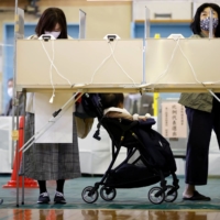 Voters fill in their ballots for the Lower House election at a polling station in Tokyo on Sunday. | REUTERS