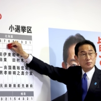Prime Minister and ruling Liberal Democratic Party leader Fumio Kishida gestures as he puts rosettes over names of successful general election candidates at the party headquarters in Tokyo on Sunday. | POOL / VIA REUTERS
